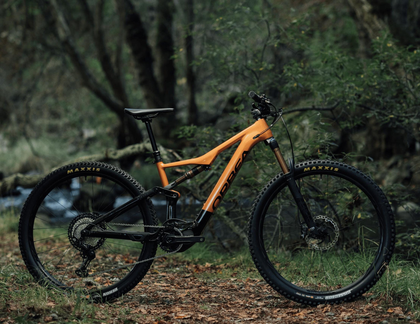 Orbea Rise Hydro H15 eMTB orange black side view forest background