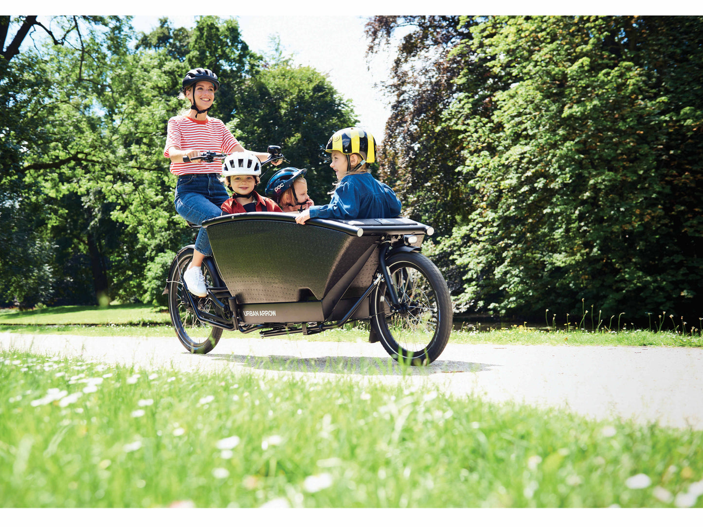 Urban Arrow Family Cargo electric bike woman with children riding bike path in park